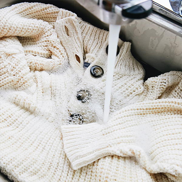 Handwashing sweater in sink.