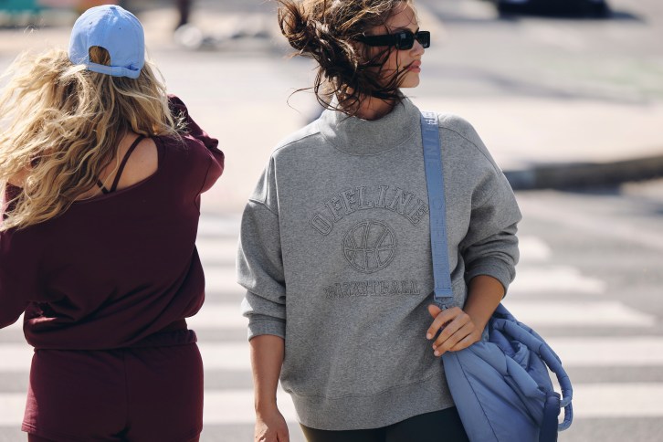 Woman wearing a dark gray mockneck sweatshirt.