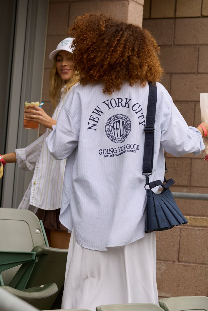 Woman wearing long white skirt and  a grey hoodie.