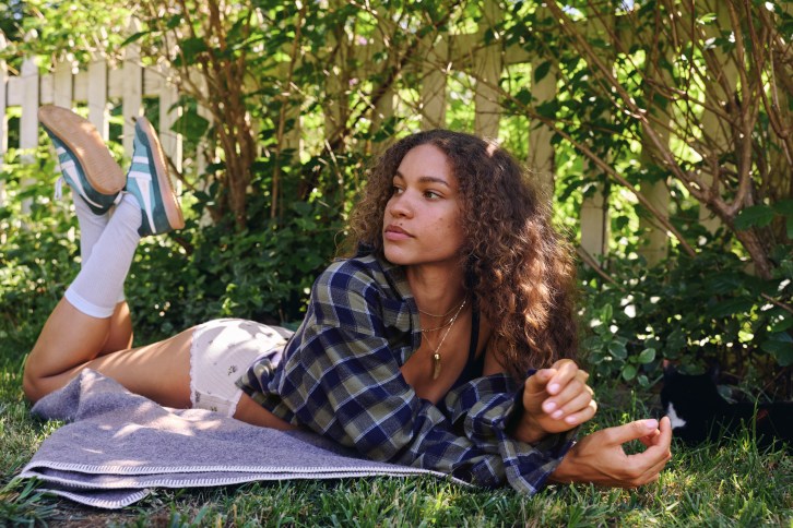 Woman wearing a flannel lying in the grass.