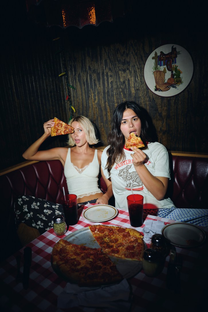 Two women wearing Aerie eating pizza.