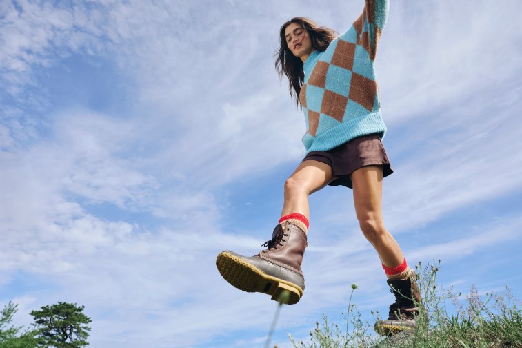 Woman in a color blocked sweater, shorts and boots.
